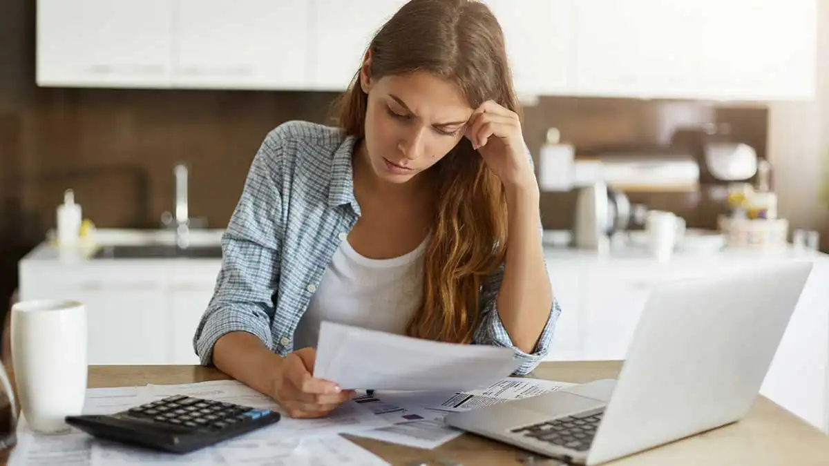 debt-blog-jul27 Person in front of laptop dealing with financial paperwork